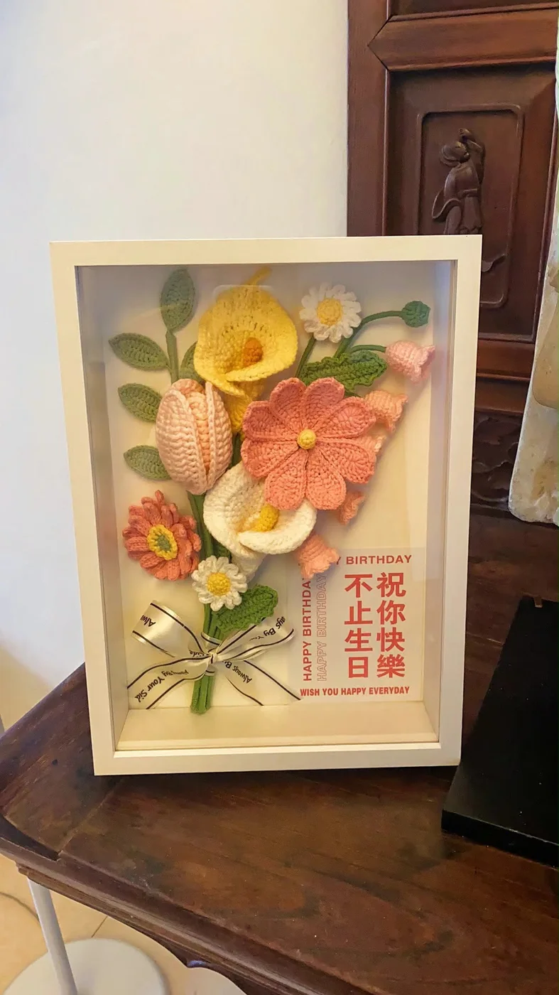 白色相框内的珊瑚色及黄色钩织花朵，配有生日祝福