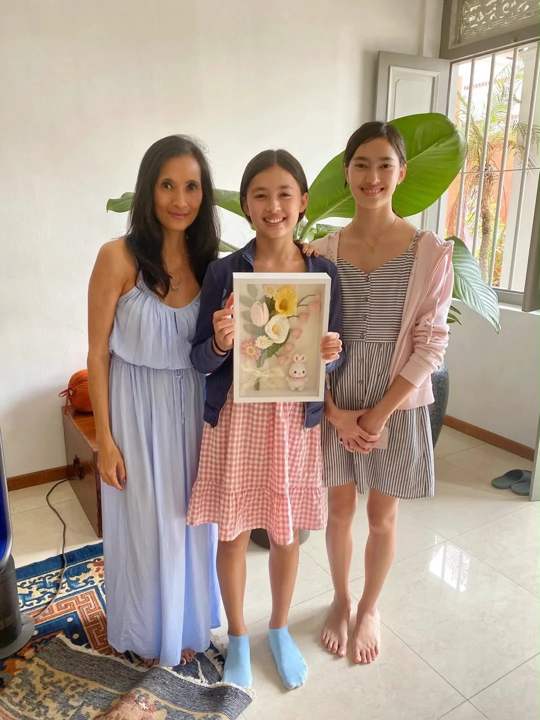 学员捧着自己完成的钩织花朵及兔子相框，与另外两人合影