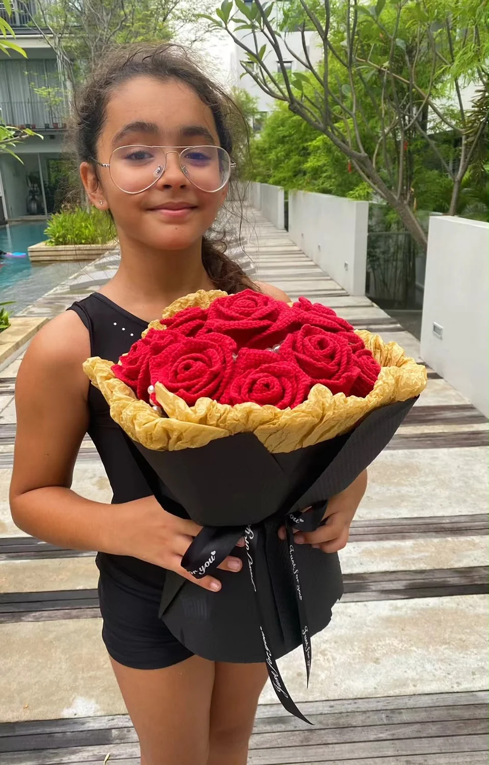 学员在户外捧着自己制作的红色钩织玫瑰花束，配黑金色包装纸